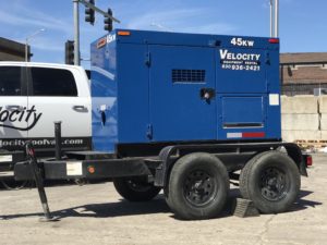 A blue generator sitting on a trailer in a parking lot