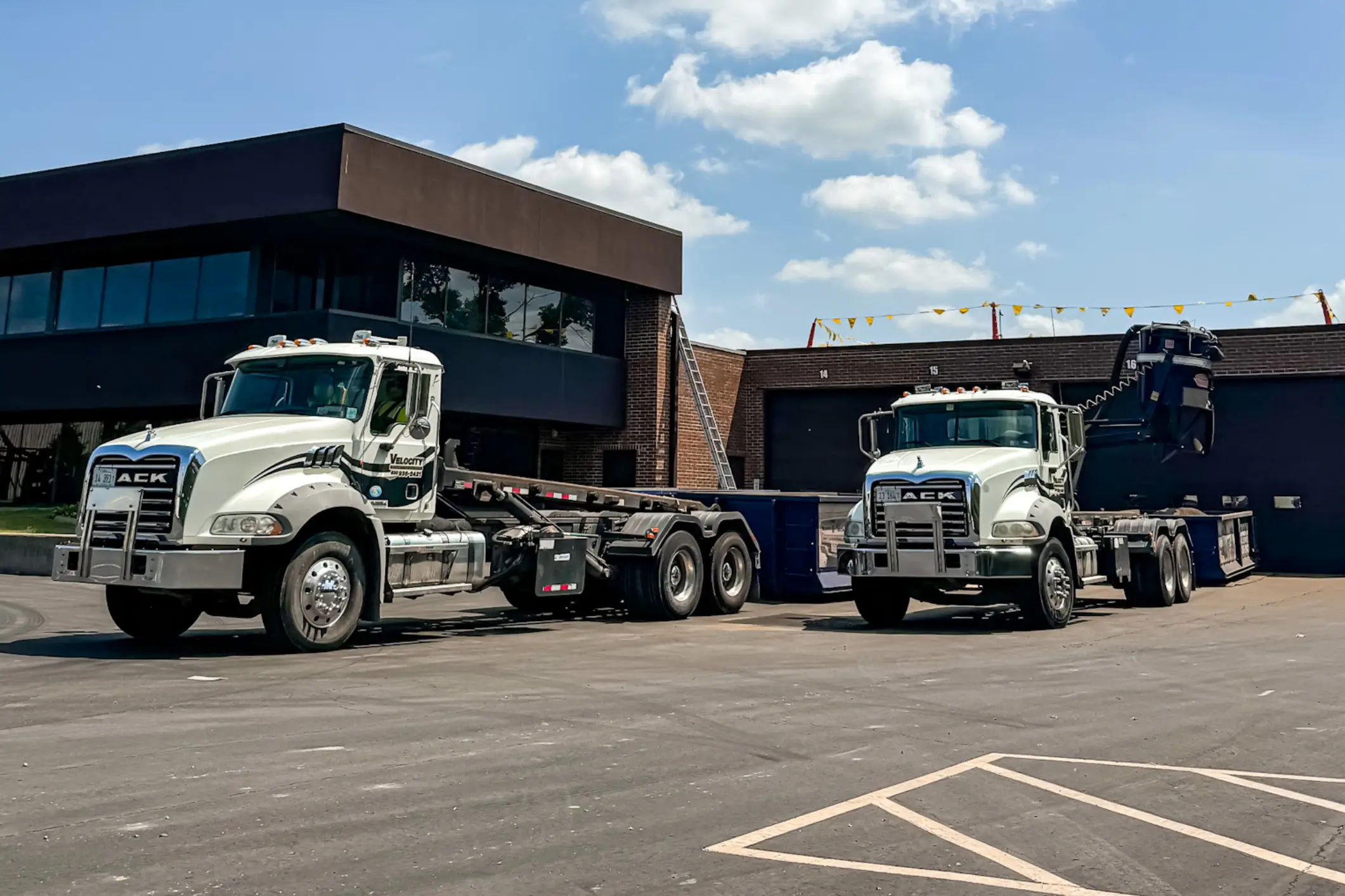 Two white heavy-duty trucks parked near building